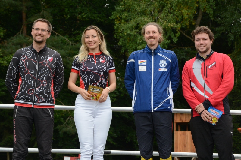 Wettkampfleiter Ralph Körner mit den Tagesbesten in MW 21 (v.l.): Oleksandra Parkhomenko (2.), Bjarne Friedrichs (1.) und Leon Kollenbach (3.).